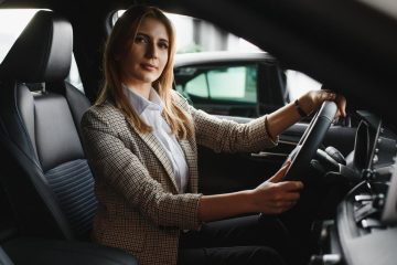 Young woman sitting behind the wheel of a car in the UAE with insurance ready